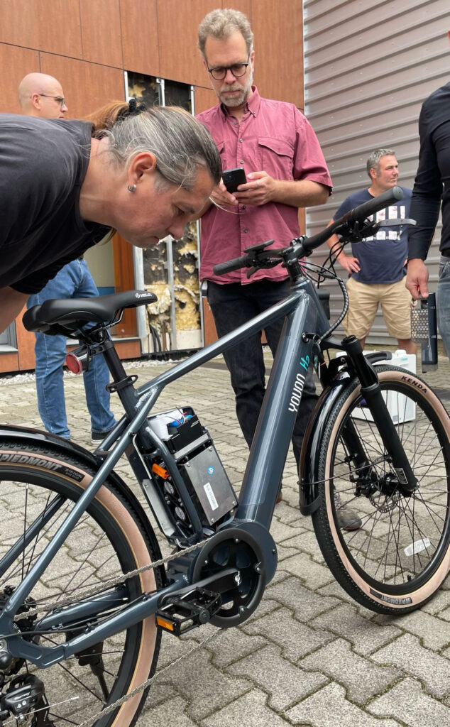 Personen stehen um ein Fahrrad mit Brennstoffzelle herum