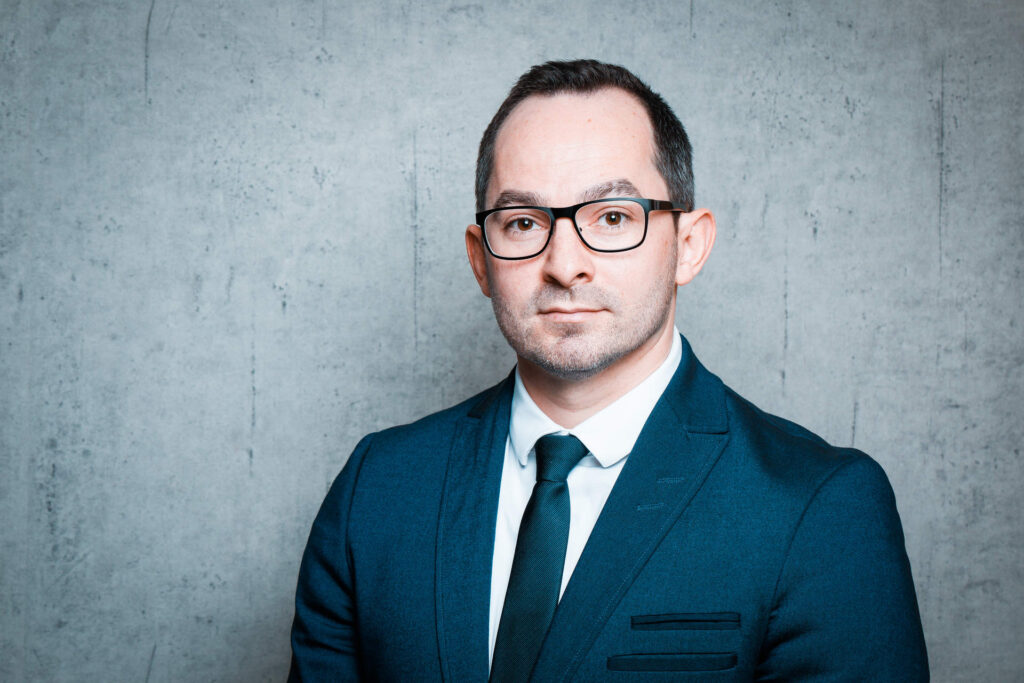 Portrait eines Manns mit Brille, Anzug und Krawatte