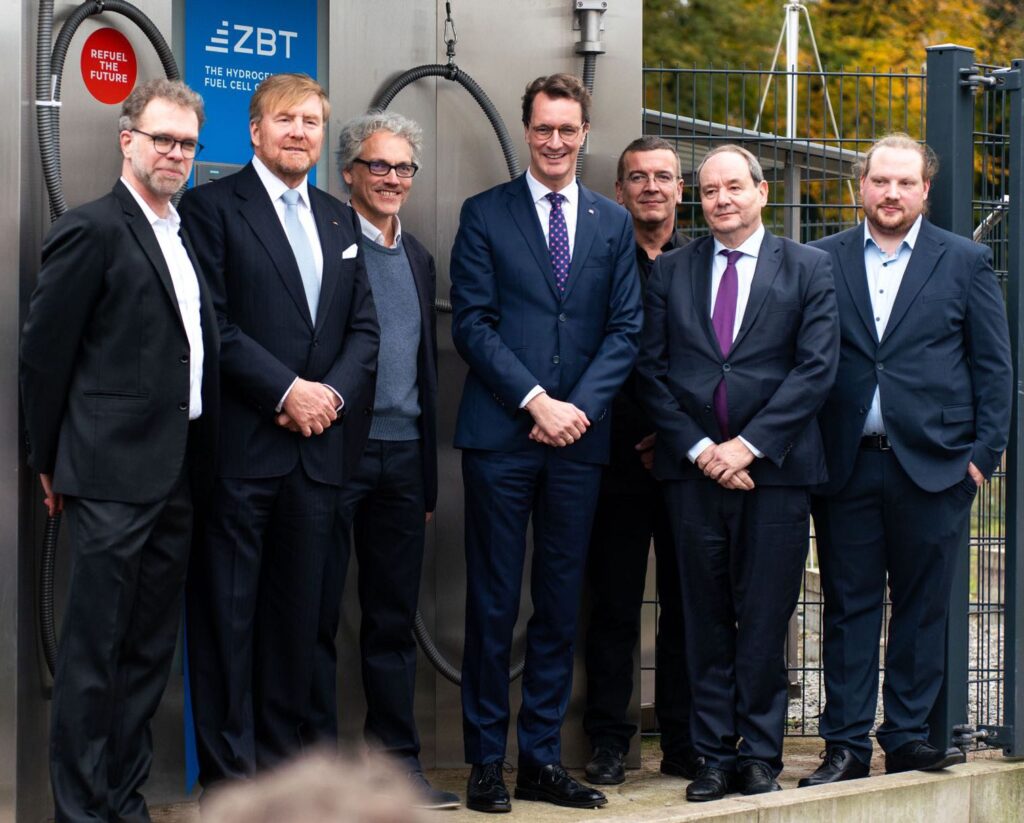 König Willem-Alexander (2.vl.) und Ministerpräsident Hendrik Wüst (Mitte) mit Funktionären aus Wirtschaft, Forschung und Politik vor der Wasserstoffzapfsäule am ZBT