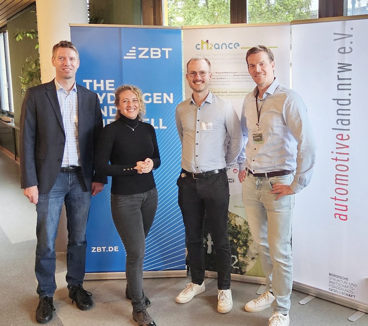 Vier Personen stehen vor drei Bannern auf der Veranstaltung: Wasserstoff-Summit 2024.