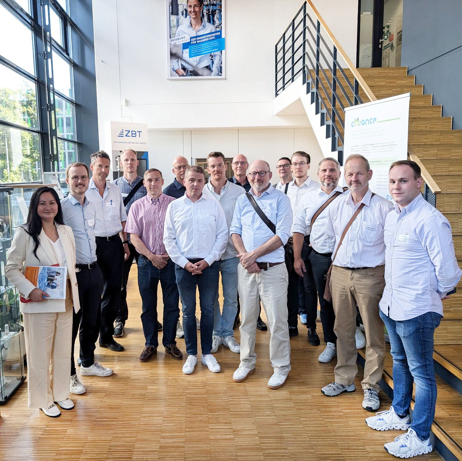 15 Personen stehen im Halbkreis zum Gruppenbild im Eingangsbereich des ZBT.