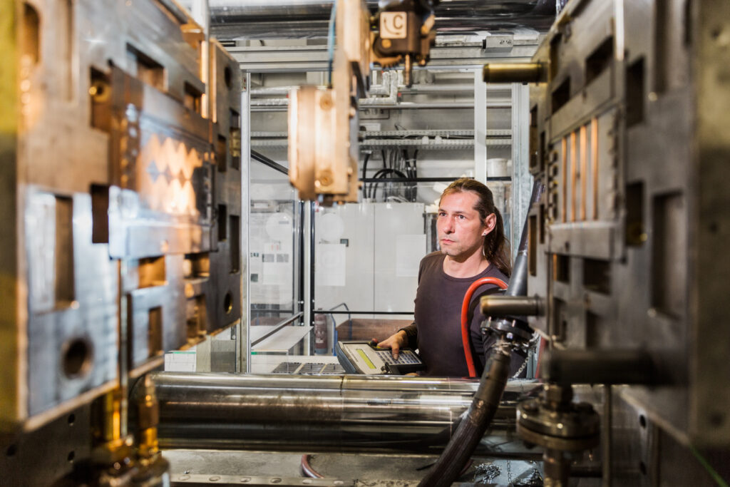 Spritzgussmaschine wird von Mitarbeiter gesteuert.