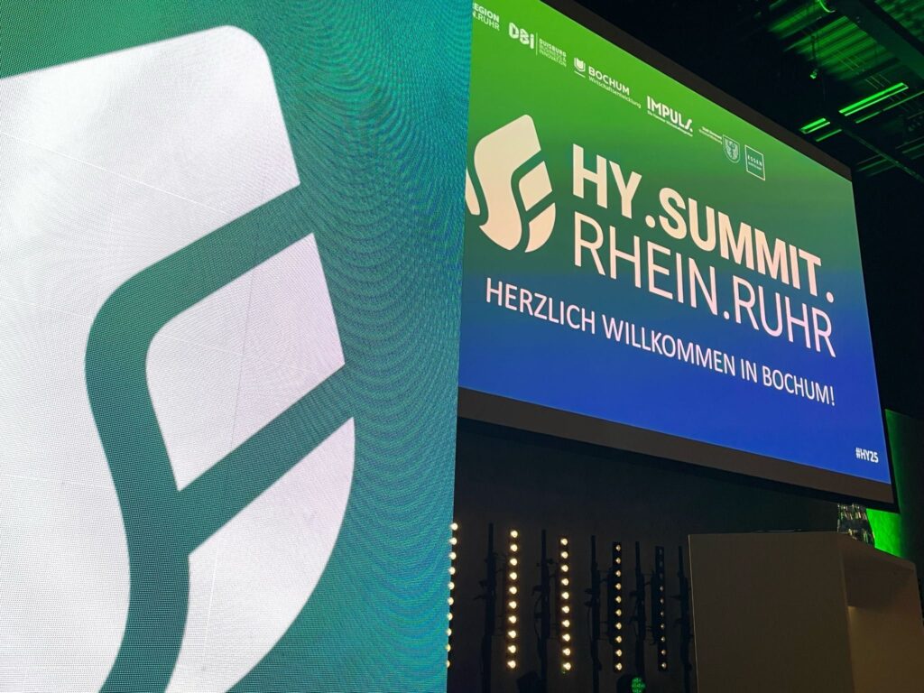 Logo und Schriftzug des Hy.Summit.Rhein.Ruhr auf Leuchtelementen an der Bühne